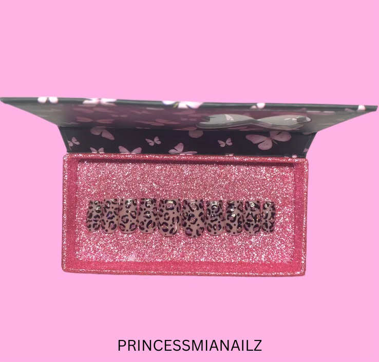 Elegant press-on nails in a lustrous pink hue, adorned with delicate butterfly motifs, presented in a stylish, glittery case from the PrincessMiaNailz nail care collection.