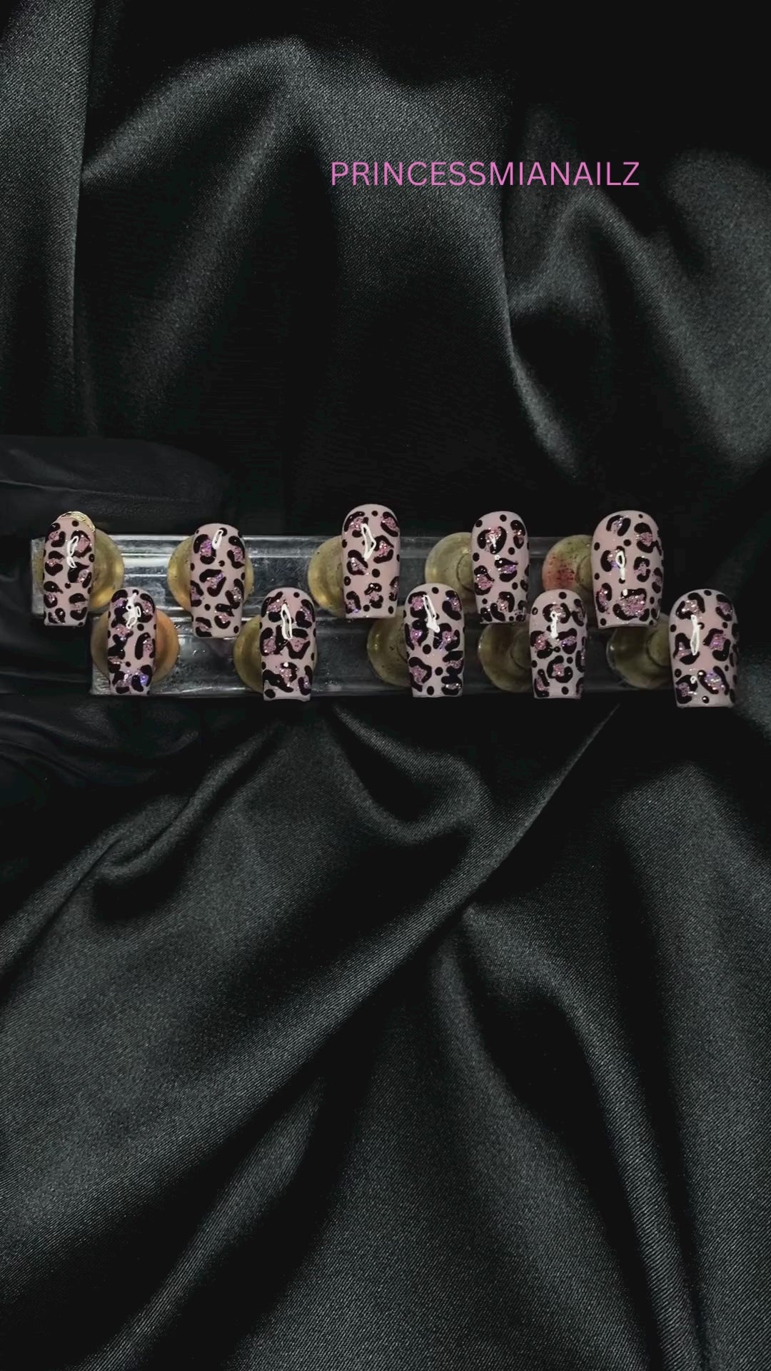 Shimmering crystal nail art display on luxurious black satin background from PrincessMiaNailz.